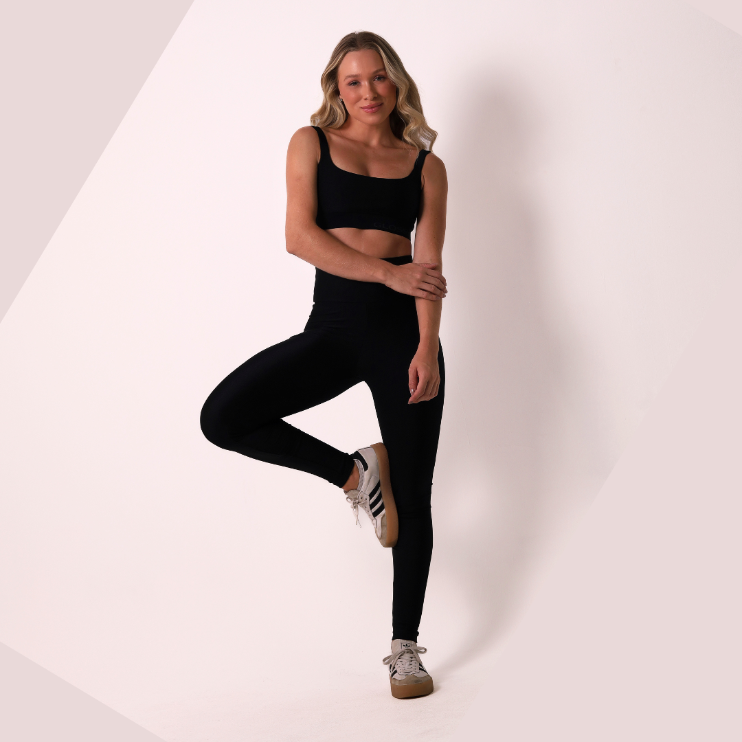 Woman wearing black athletic wear posing on a white background